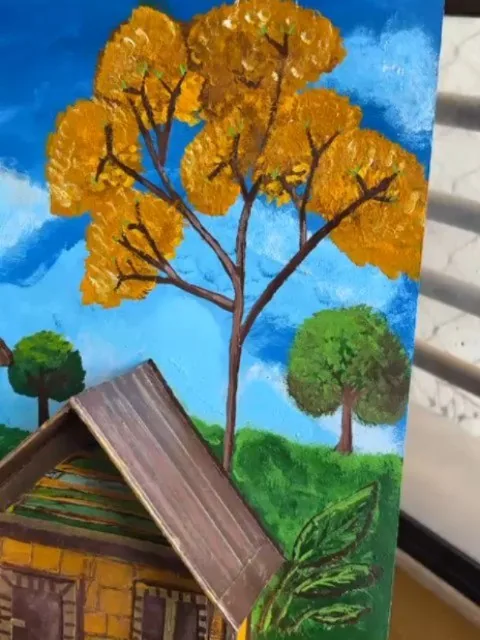 Detalhe de pintura à mão com ipê amarelo florido, céu azul e telhado de uma casinha de madeira
